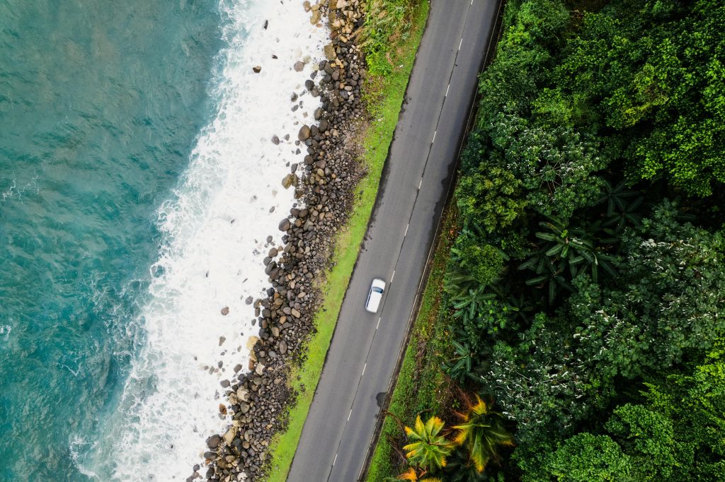 Aerial shot of a scenic coastal road in Spring Garden, Jamaica, next to lush greenery and blue ocean.